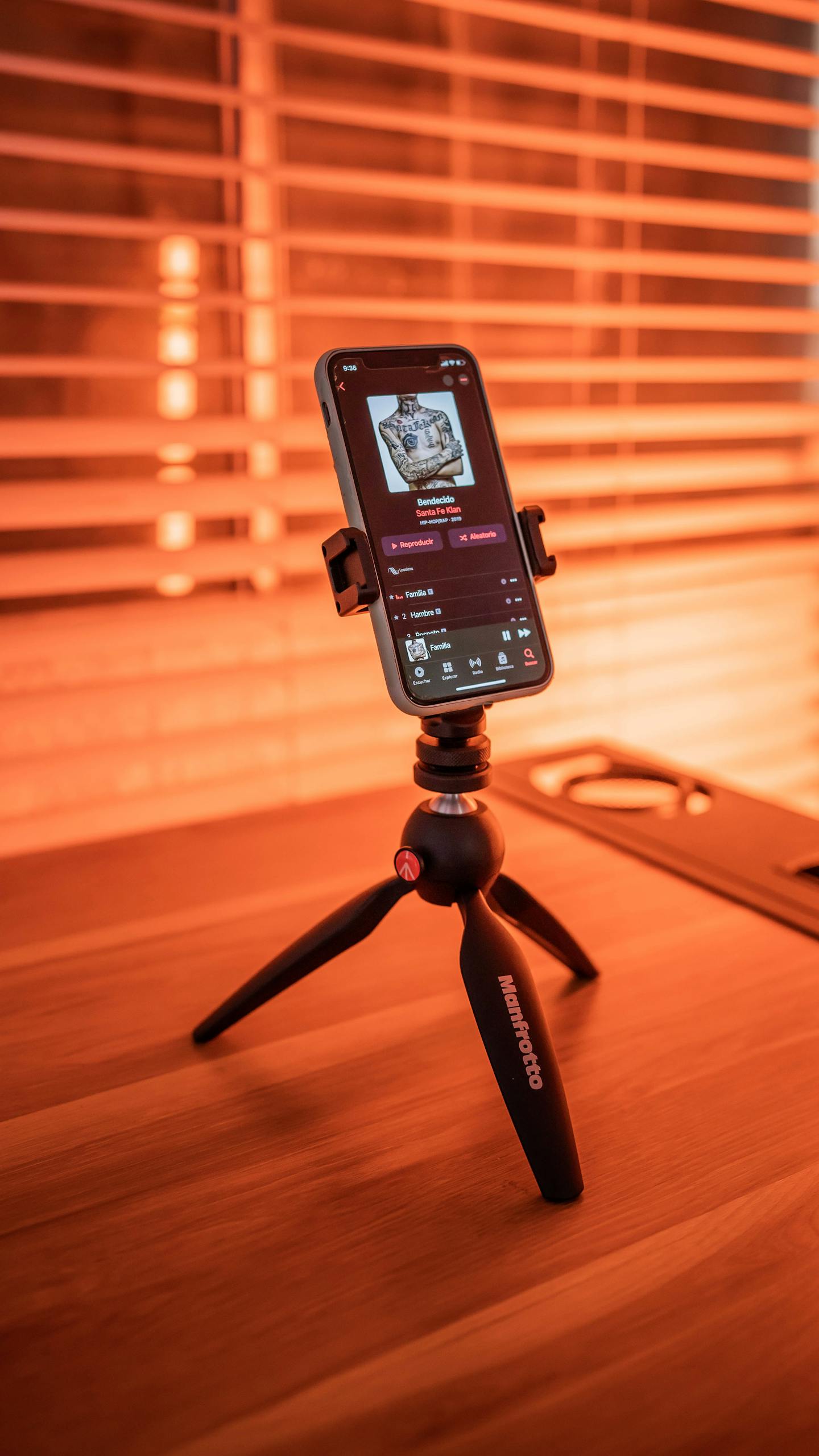Smartphone mounted on a tripod playing music indoors with warm ambiance.
