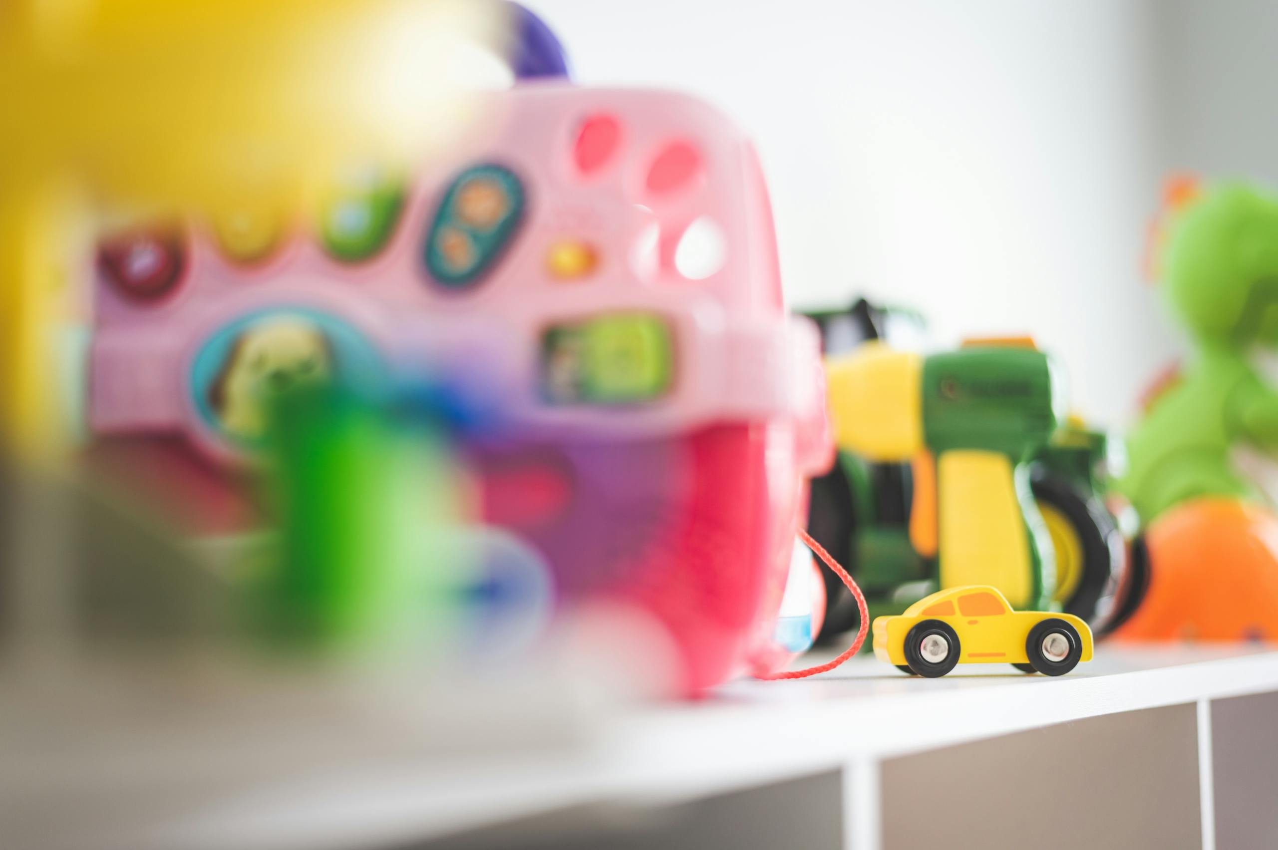 Vibrant collection of children's toys featuring a miniature yellow car in focus.